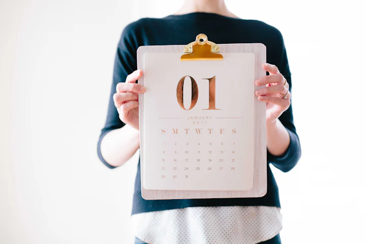 Person holding up a monthly calendar on a clipboard